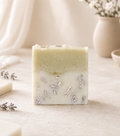 Handmade lavender soap bar with soothing lavender petals and a soft botanical design, crafted with natural ingredients and displayed in a warm, minimalist spa-inspired setting.