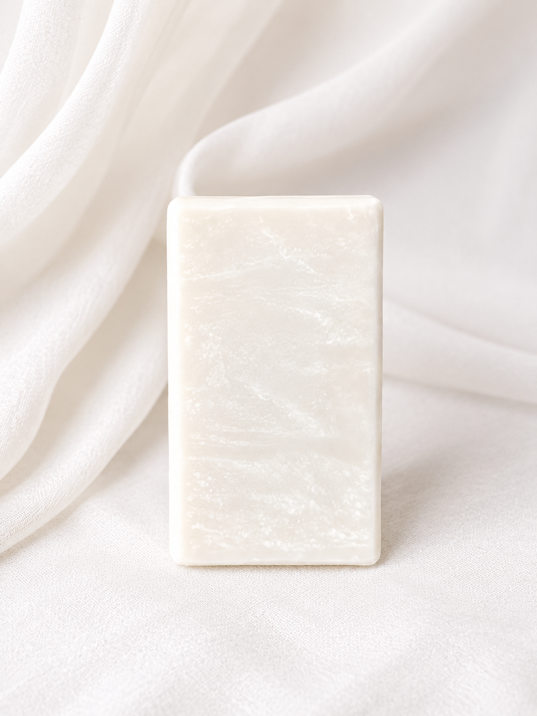 Natural handmade soap bar with a creamy white marbled design, crafted with plant-based ingredients and photographed on a soft neutral fabric backdrop for a clean, minimalist skincare aesthetic.