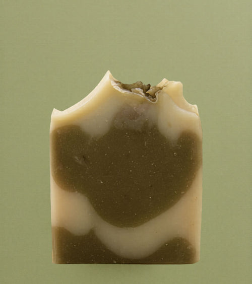Handcrafted clove bud soap bar with a creamy beige base and earthy brown swirl design, featuring a textured, rustic top edge against a soft neutral background.